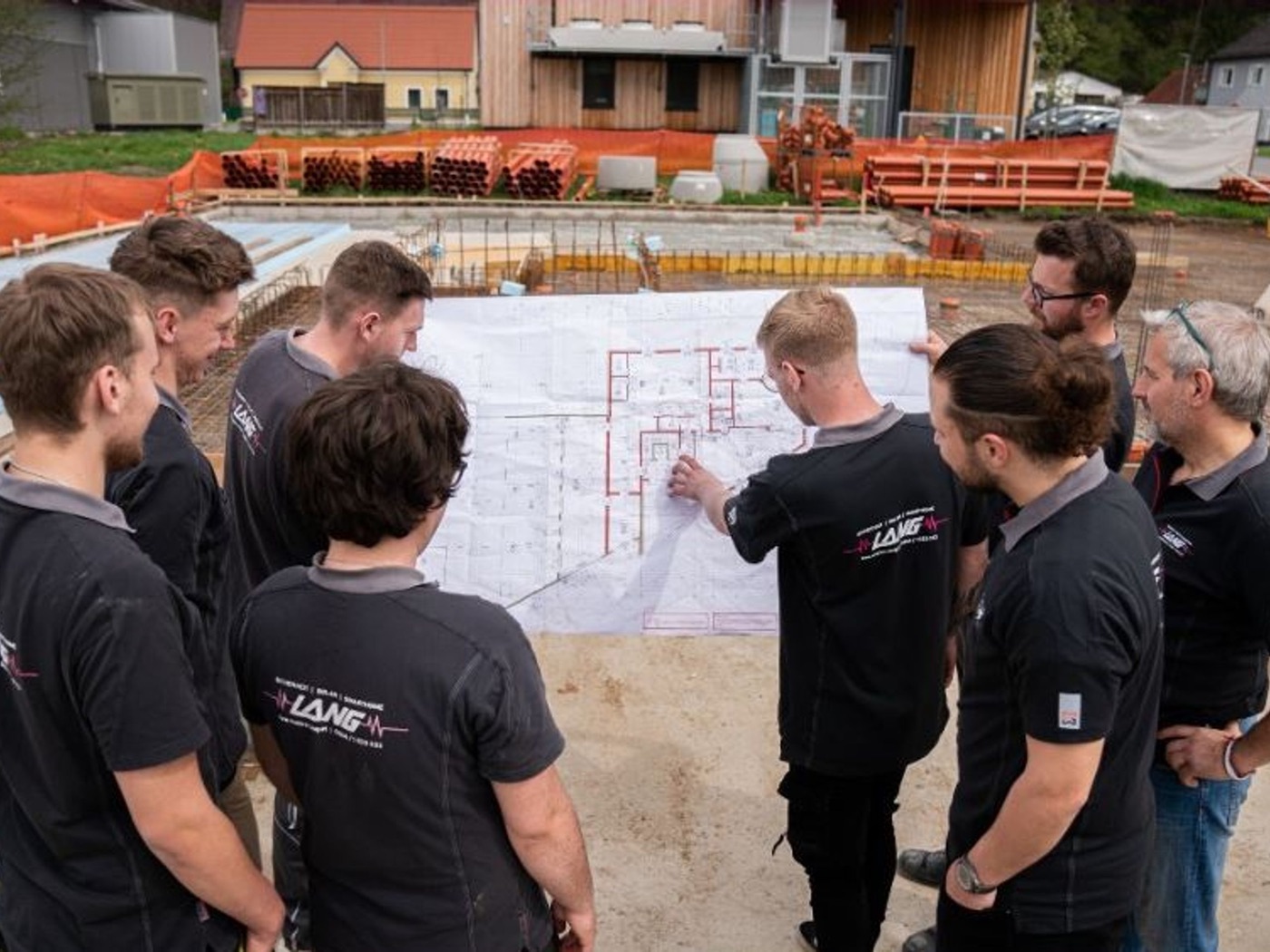 Team von Elektro Lang bespricht einen Bauplan auf der Baustelle