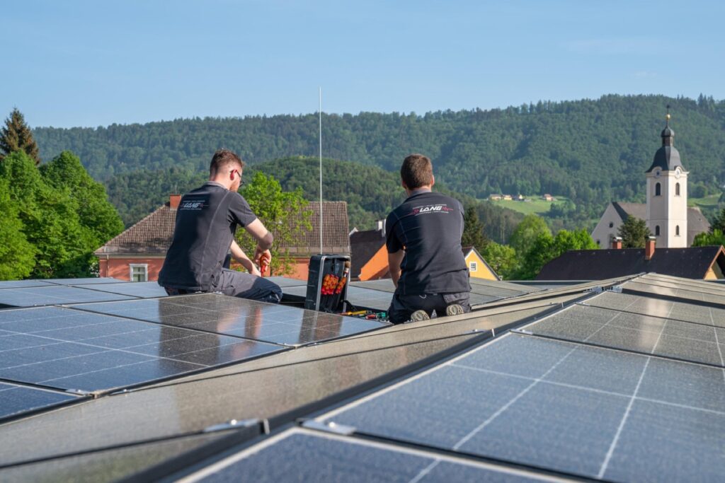 Zwei Techniker von Elektro Lang montieren Photovoltaikmodule auf einem Dach